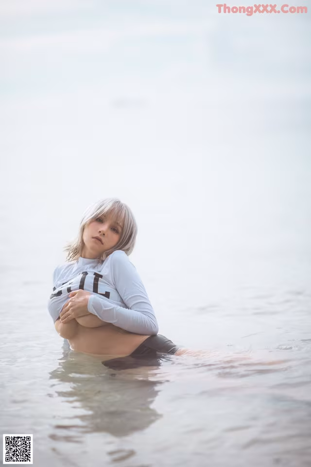 A woman sitting in the water with her arms crossed.