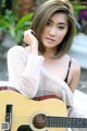 A woman sitting on a bench holding a guitar.