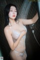 A woman in a white lingerie standing in a shower.