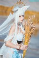 A woman in a white dress holding a bunch of wheat.