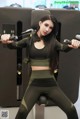 A woman in a black and green outfit is working out in a gym.