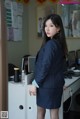 A woman in a business suit standing in front of a desk.