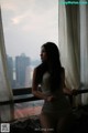 A woman sitting on a bed looking out a window.