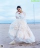 A woman in a white dress standing on a beach.