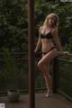 A woman in a black bikini standing on a wooden deck.