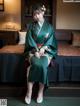 A woman in a green kimono sitting on a bed.