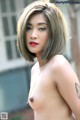 A naked asian woman with a tattoo on her arm.