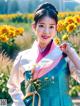 A woman in a hanbok standing in a field of sunflowers.