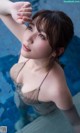 A woman in a brown bikini sitting in a pool.