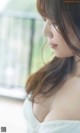 A woman in a white dress looking out a window.