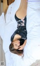 A woman laying on top of a bed in a black dress.